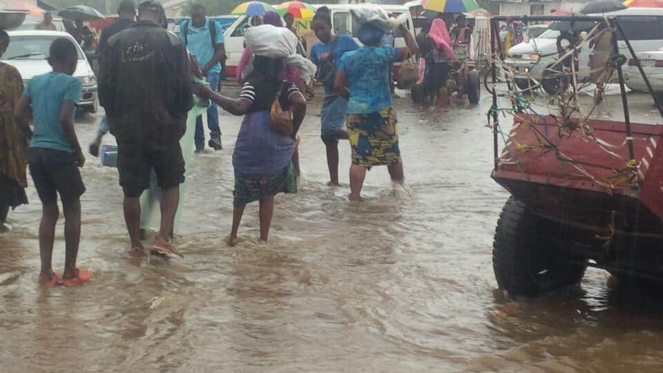 Des passants obligés des marchés dans la boue et l'eau de pluie